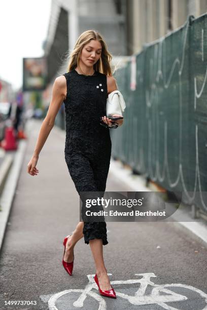 Guest wears a black ruffled embossed tank-top / long tube dress, a white matte leather handbag, black sunglasses, red shiny varnished leather pointed...