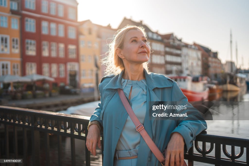 Caucasian Female Radiates Joy as She Takes a Delightful Walk by the Riverbank in Copenhagen