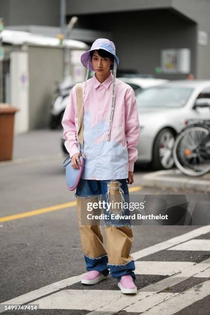 Guest wears pale blue and pale pink bicolored bob hat from JW Anderson, a matching pale blue and pale pink bicolored long shirt, a navy blue denim...