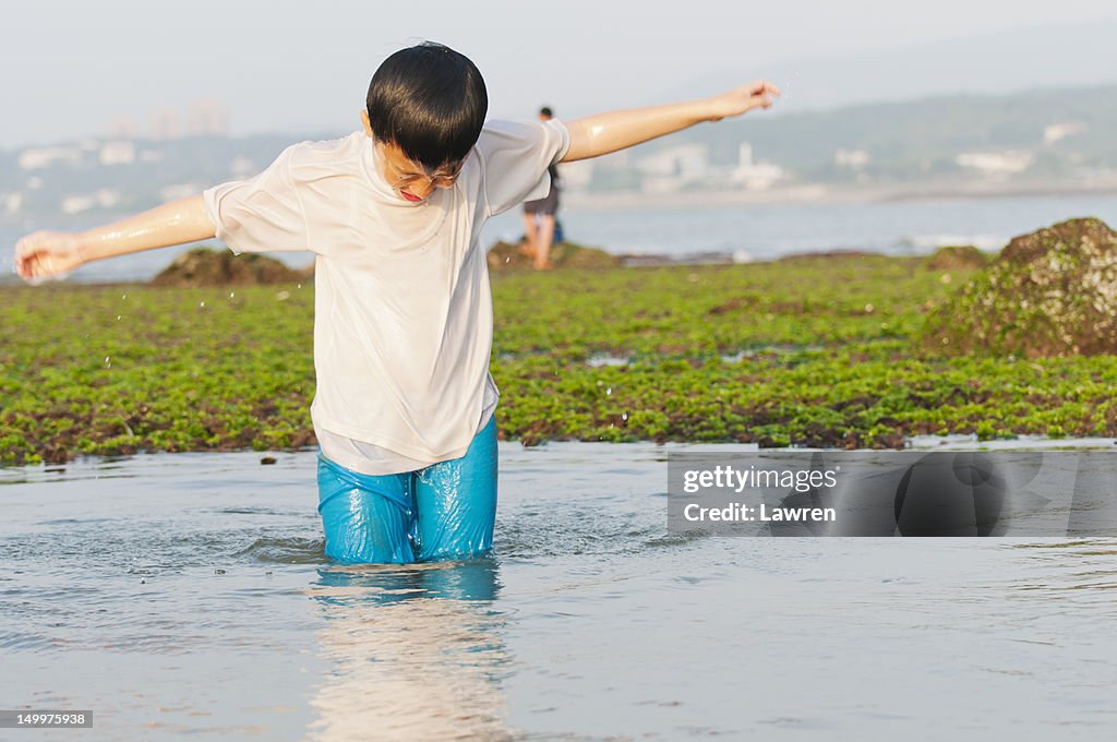 Boy standing up from water at seacoast