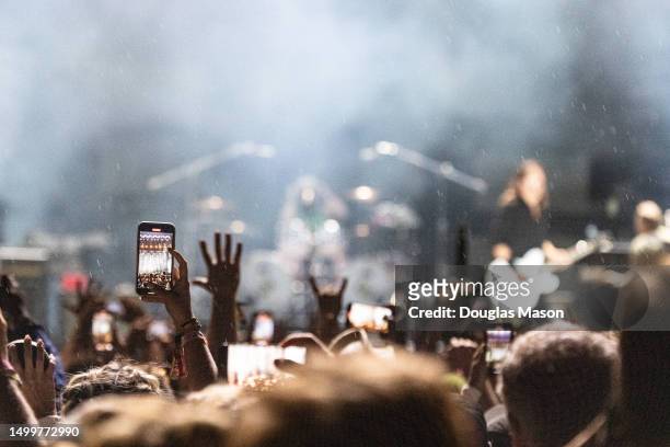 Fans staking pictures in the rain at the Bonnaroo Music and Arts Festival on June 18, 2023 in Manchester, Tennessee.