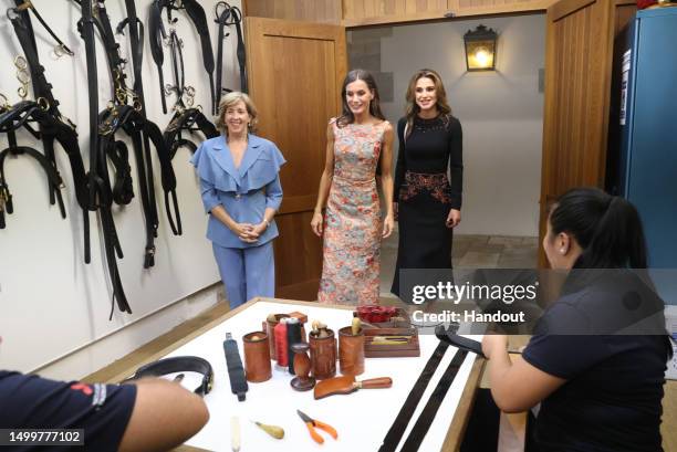 In this handout provided by the Spanish Royal Household, Queen Letizia of Spain and Queen Rania of Jordan visit the saddlery workshop in the National...