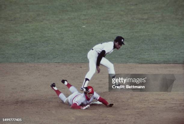New York Yankee second baseman Willie Randolph leaps high to avoid a slide by the Cincinnati Reds' shortstop Dave Concepcion after making a throw to...