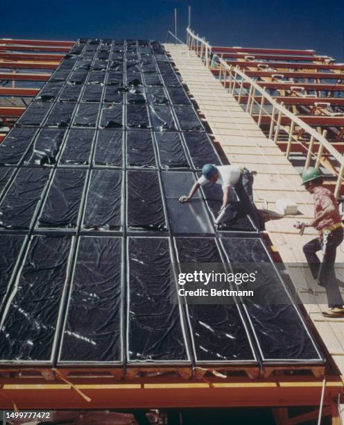 Workers installing solar panels at the new National Security and Resources Study Center of the Los Alamos Scientific Laboratory in New Mexico,...