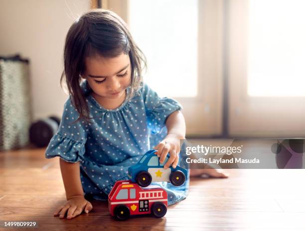 toddler girl playing with toy vehicles - jugar fotografías e imágenes de stock