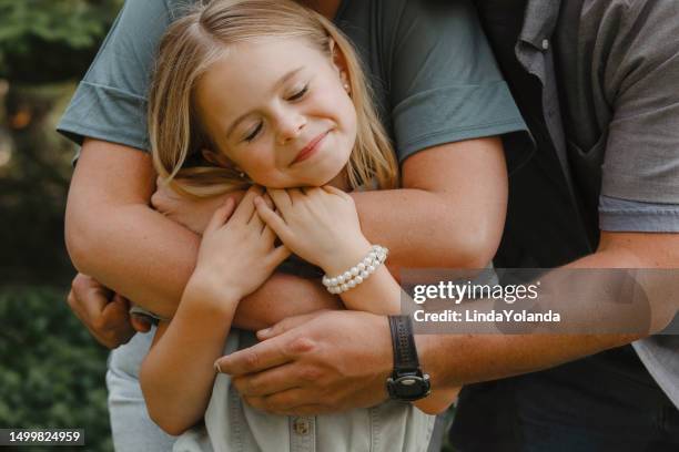 little girl being hugged by parents - seven generations stock pictures, royalty-free photos & images