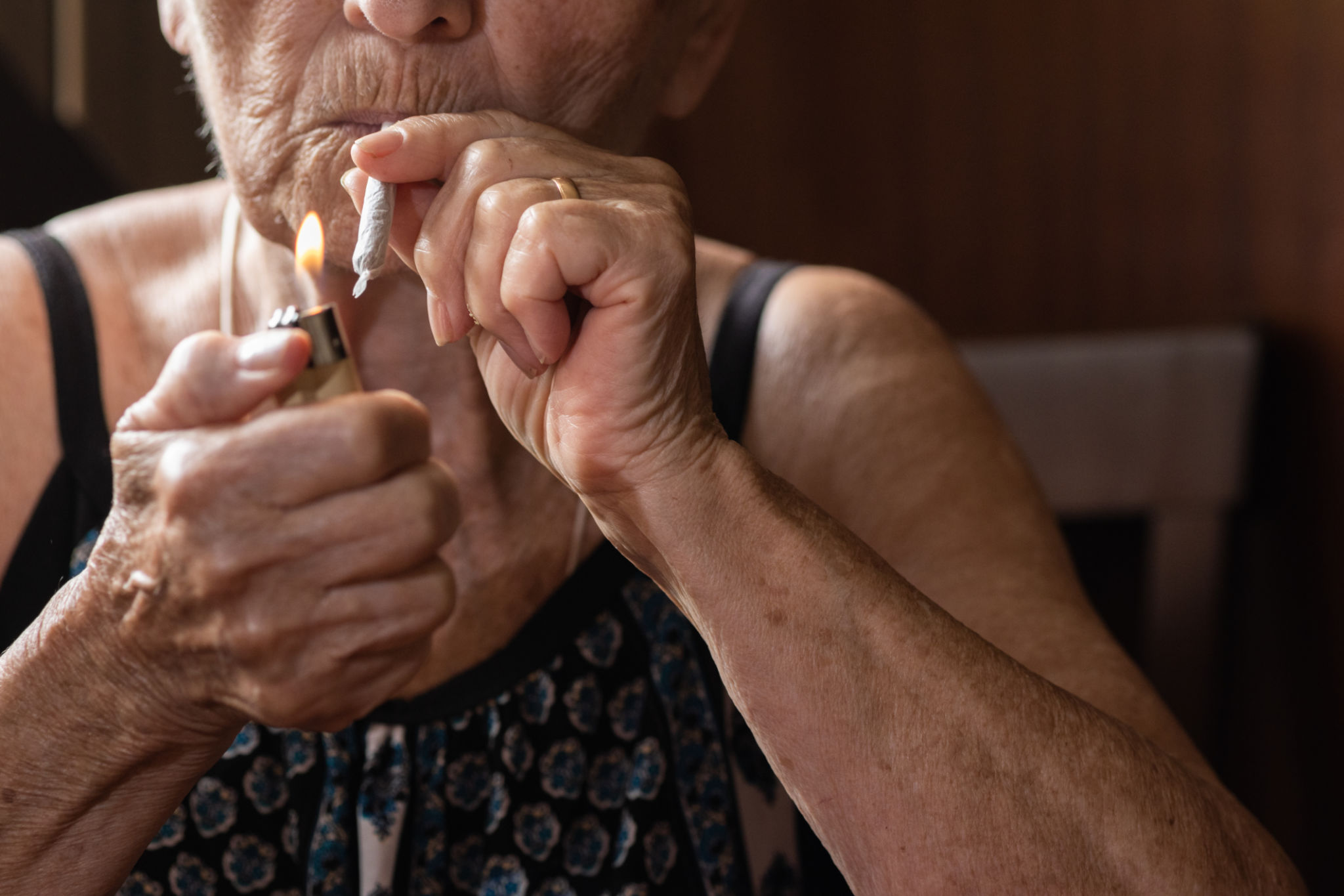 unrecognizable old woman lighting a joint of marijuana with the flame of a lighter. concept of medical cannabis and cbd and thc. unrecognizable old woman lighting a joint of marijuana with the flame of a lighter. concept of medical cannabis and cbd and thc.
