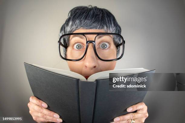 funny fisheye nerdy woman looking up from book - thick reading glasses stock pictures, royalty-free photos & images