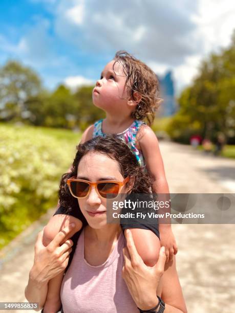 toddler age girl sitting on the shoulders of her mother while on a walk - mitt på dagen bildbanksfoton och bilder