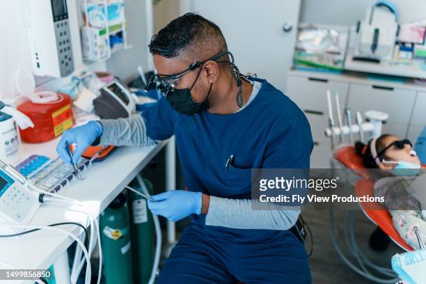 dentista masculino se prepara para limpiar los dientes de su paciente - odontopediatría fotografías e imágenes de stock
