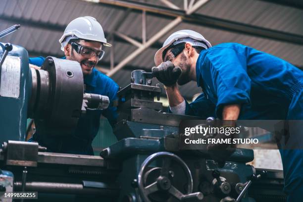 2 young engineers are workers and engineers in the factory helping to produce and form steel by working with the factory machines, including lathes and rolling machines. - stage set stockfoto's en -beelden