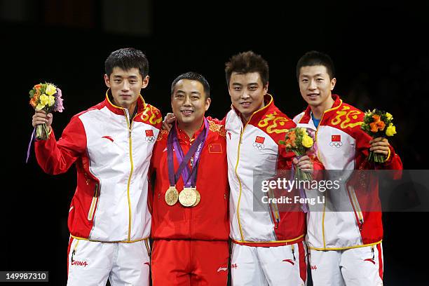 Gold medalists Ma Long , Wang Hao and Zhang Jike of China celebrate with their coach Liu Guoliang after putting their medals around his neck during...