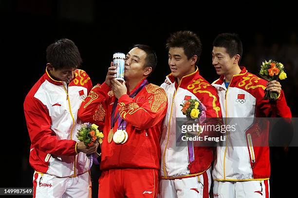 Gold medalists Ma Long , Wang Hao and Zhang Jike celebrate with their coach Liu Guoliang of China after putting their medals around his neck during...