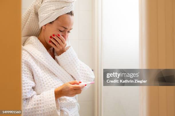 woman reacting to pregnancy test result, covering her mouth with her hand - lazio medical tests stock pictures, royalty-free photos & images
