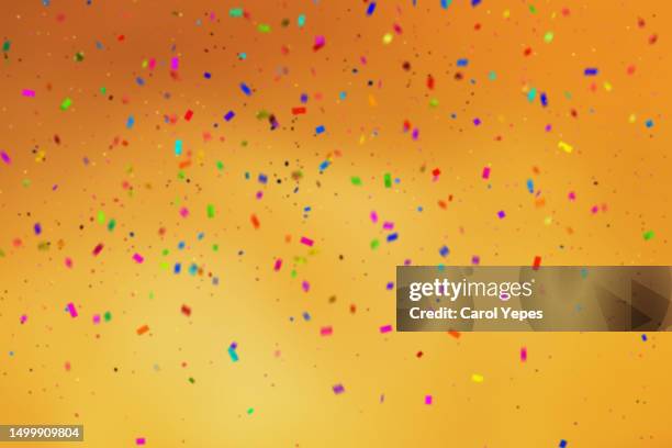 falling confetti in orange background - birthday streamers stock-fotos und bilder