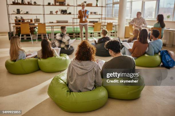 rear view of students having a class at casual classroom. - bean bag stock pictures, royalty-free photos & images