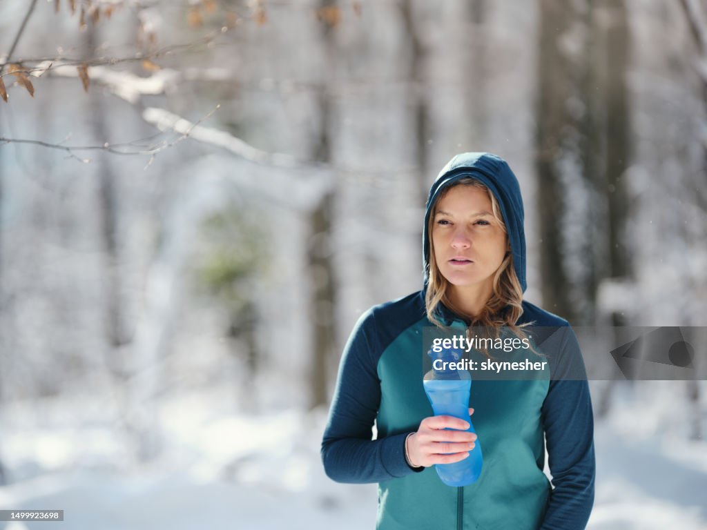 Femme athlétique ayant une pause eau en journée d’hiver.