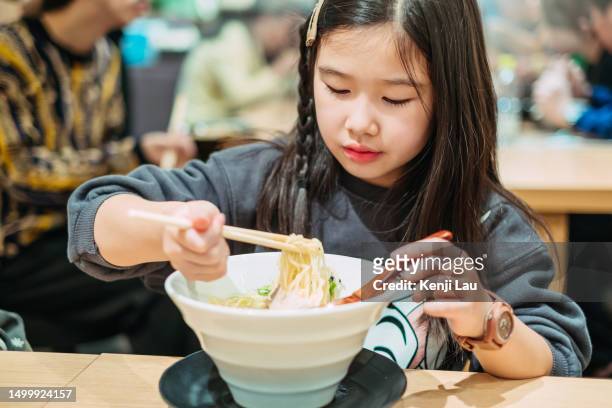 little asian tourist girl enjoying japanese traditional ramen noodles in restaurant in osaka while travelling japan. food, eating outside, japanese culture, carefree, childhood, vacation, family day, family outdoor weekend activities. - japanese chopsticks stock pictures, royalty-free photos & images