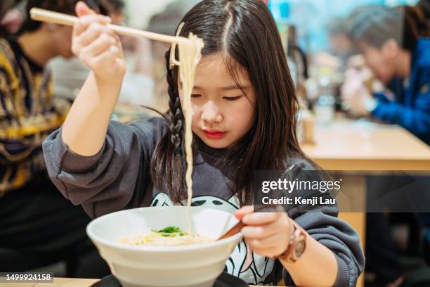 little asian tourist girl enjoying japanese traditional ramen noodles in restaurant in osaka while travelling japan. food, eating outside, japanese culture, carefree, childhood, vacation, family day, family outdoor weekend activities. - japanese chopsticks stock pictures, royalty-free photos & images