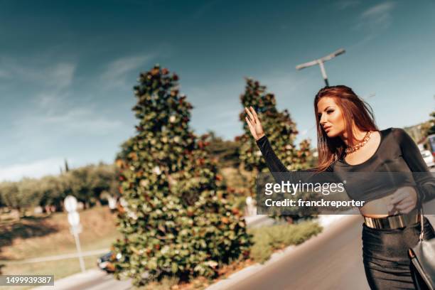 fashion woman in a black dress in the city hailing a ride - air taxi stock pictures, royalty-free photos & images