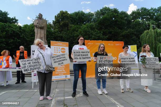 Women with make-up on their faces in the form of cuts and bruises typical of victims of domestic or sexual violence hold placards with the...