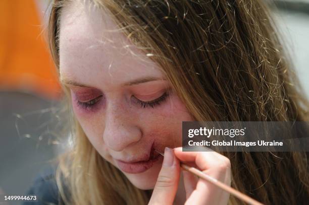 Make-up artist applies make-up to a participant of the "Break The Silence" street performance in the form of cuts and bruises typical of victims of...