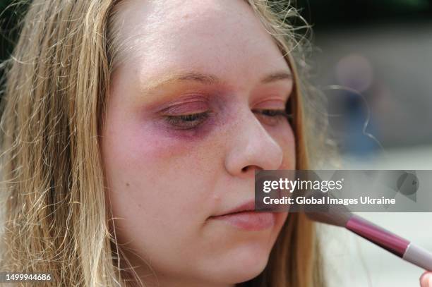 Make-up artist applies make-up to a participant of the "Break The Silence" street performance in the form of cuts and bruises typical of victims of...