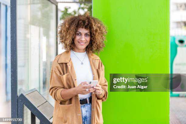 merry adult female using mobile phone near green poster - roll up banner stock pictures, royalty-free photos & images