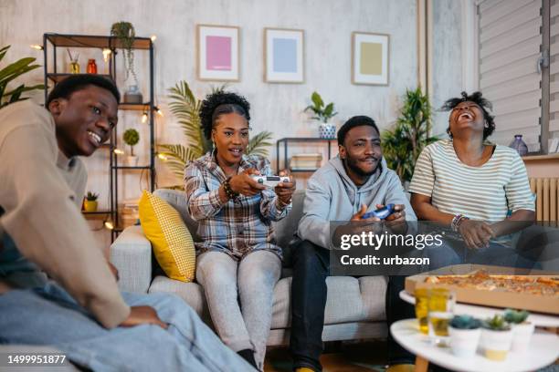 friends sitting together playing video games at home - adrenaline junkie stock pictures, royalty-free photos & images