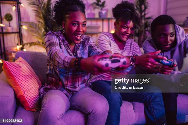 group of friends having fun playing video games at home at night - adrenaline junkie stock pictures, royalty-free photos & images