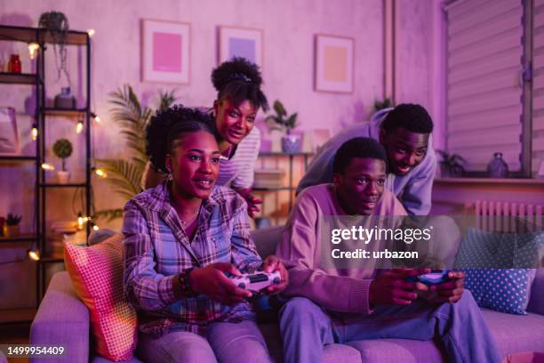 group of friends having fun playing video games at home at night - adrenaline junkie stock pictures, royalty-free photos & images