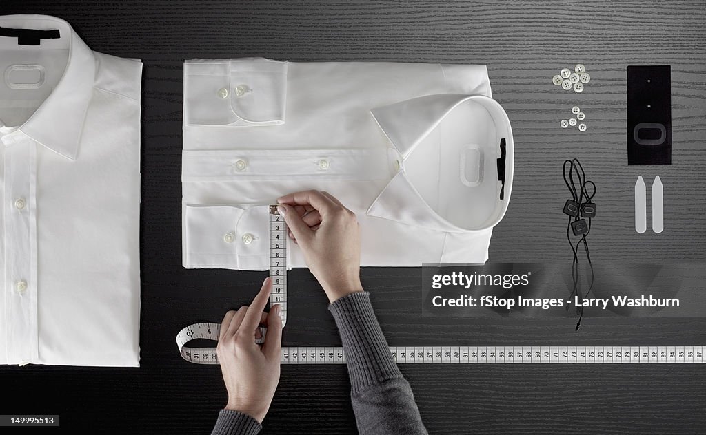 A tailor measuring a button down shirt, focus on hands