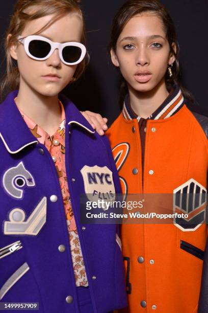 Backstage at the Coach show during New York Fashion Week Autumn/Winter 2016/17, two models wear colourful varsity jackets in violet and bright orange...