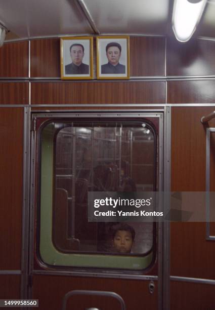 Young North Korean pauses as he commutes on the subway, where portraits of the late leaders Kim Il Sung and Kim Jong Il are displayed inside the...