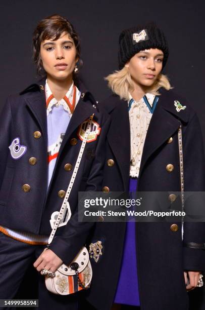 Backstage at the Coach show during New York Fashion Week Autumn/Winter 2016/17, two models wear a dark wool varsity jacket and coat with double rows...