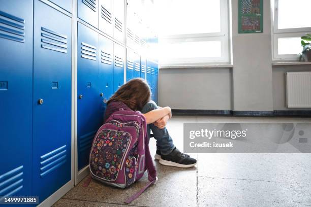 ragazza triste della scuola che si siede nel corridoio della scuola - scolara foto e immagini stock