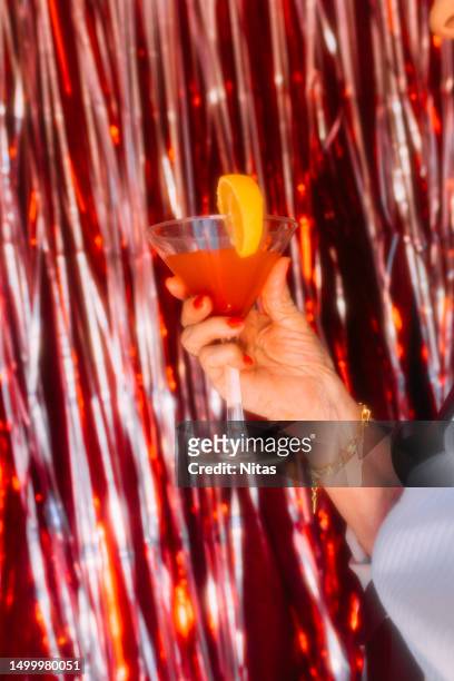 elderly woman hand holding a bloody mary cocktail - cocktail ring stock-fotos und bilder