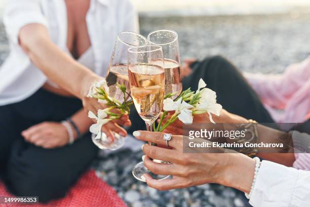 three woman clink their glasses together in a celebratory toast on the beach by the sea. - asian female friends drinking soda outdoor stockfoto's en -beelden