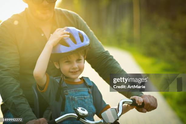 little boy with his father riding a bicycle in summer evening - spring weather stock pictures, royalty-free photos & images