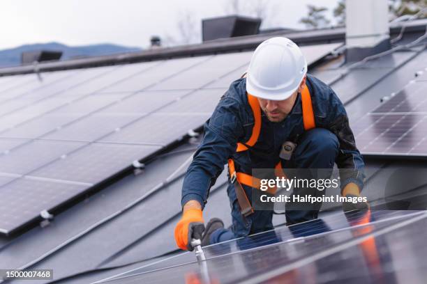 worker installing solar panels on the roof. - zonnepanelen stockfoto's en -beelden