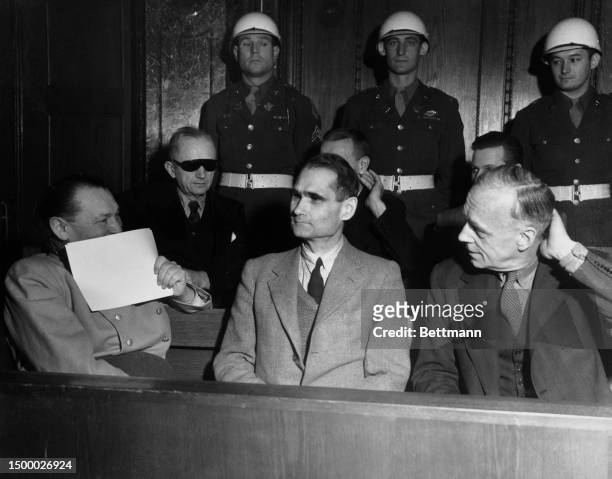 Hermann Goering uses a paper to cover up a smile as he exchanges jovialities with Rudolf Hess and Joachim von Ribbentrop before the start of a...