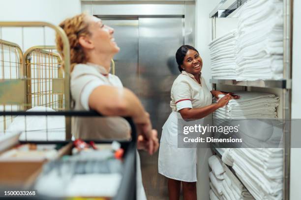 interracial hotel maids having fun conversation in laundry - reinier stockfoto's en -beelden