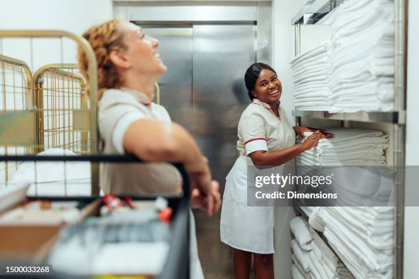 interracial hotel maids having fun conversation in laundry - arrumado imagens e fotografias de stock