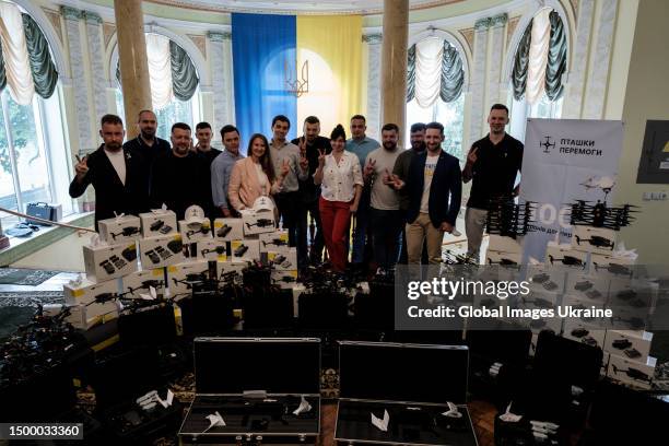 Volunteers pose for the camera, standing next to drones and quadcopters purchased for the Armed Forces of Ukraine on June 19, 2023 in Lviv, Ukraine....