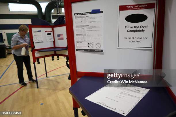 Polling station volunteer cleans a voting booth at a polling station in Arlington County at Nottingham Elementary School June 20, 2023 in Arlington,...