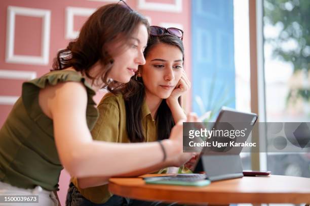 young female adults meets at coffee shop, using digital tablet - study abroad stock pictures, royalty-free photos & images