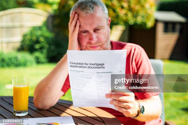 mann, der hypothekenantragsunterlagen liest - hypothek stock-fotos und bilder