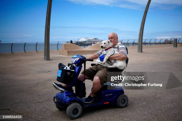 Dog hitches a lift from its owner on Blackpool's promenade as the Lancashire seaside resort gears up for the Summer holidays on June 20, 2023 in...