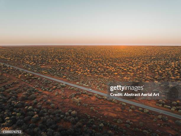 idyllic scene showing a car driving through the australian outback on a highway at sunset, western australia, australia - bush australien photos et images de collection