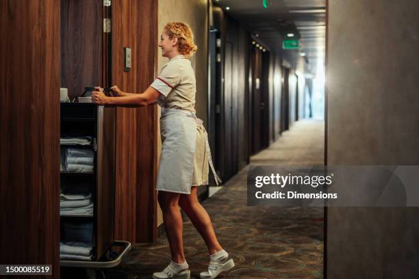 blondes dienstmädchen schiebt sanitärwagen in den raum - hotelzimmer tür stock-fotos und bilder